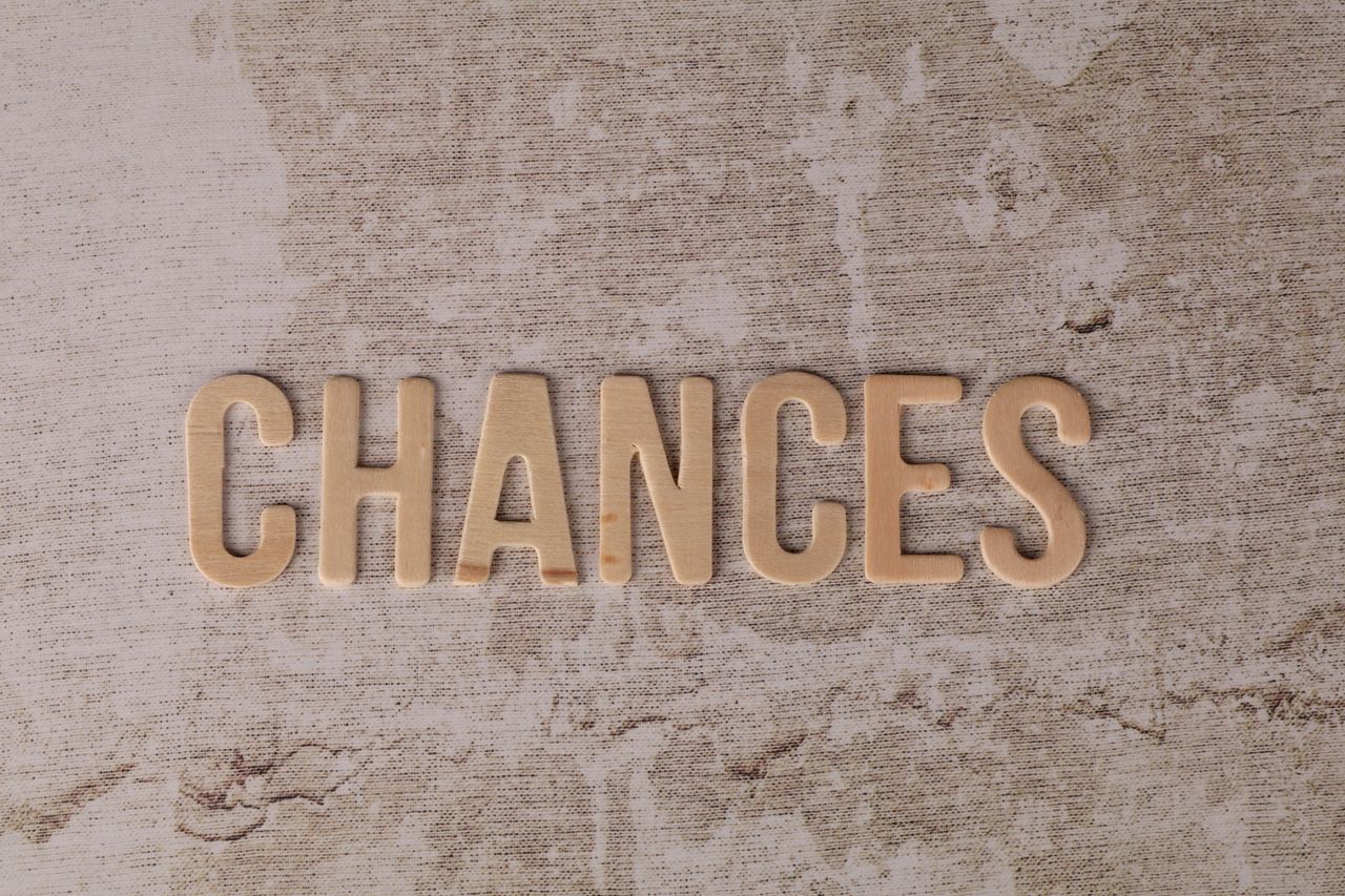 The word 'CHANCES' in wooden letters on a textured, rustic surface.