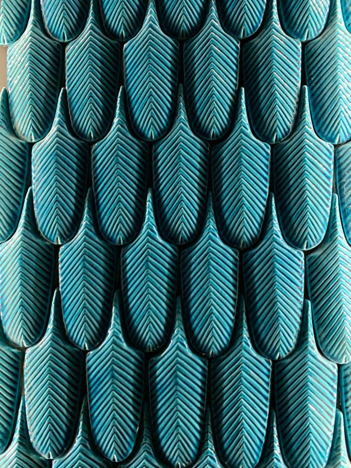 Close-up of blue leaf-shaped tiles forming a textured, abstract pattern.